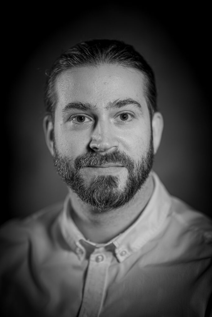 Ein jüngerer Herr mit Vollbart, Foto in schwarzweiß.